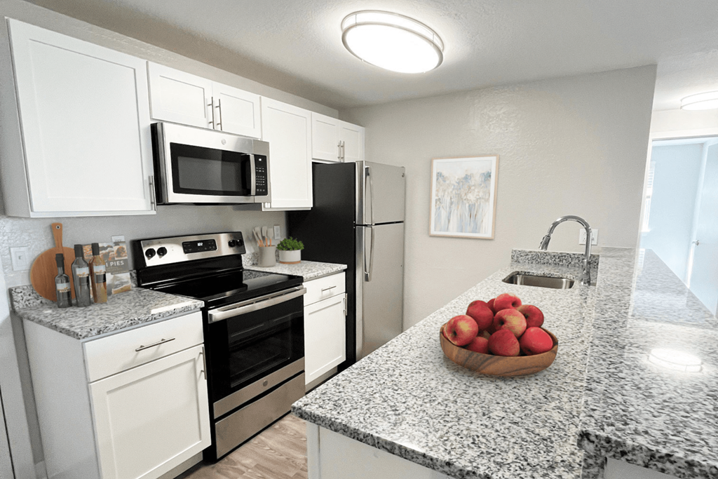 a kitchen with white cabinets, granite counter top and stainless steel appliances at The Meadows in Chelmsford, MA