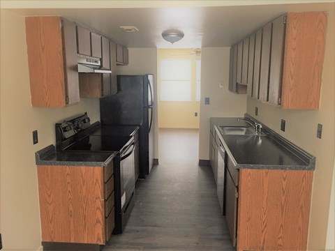 an empty kitchen with wooden cabinets and a black stove and refrigerator