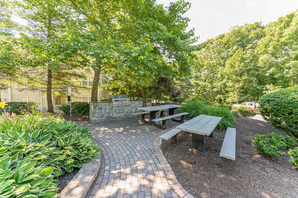 a picnic table and benches in a park with trees  at Cumberland Crossing, Cumberland, Rhode Island