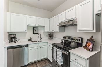 A small white kitchen with a black stove top oven.