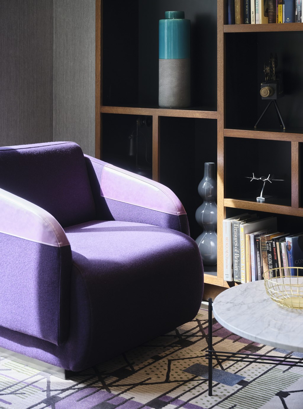 A purple chair sits in front of a bookshelf.