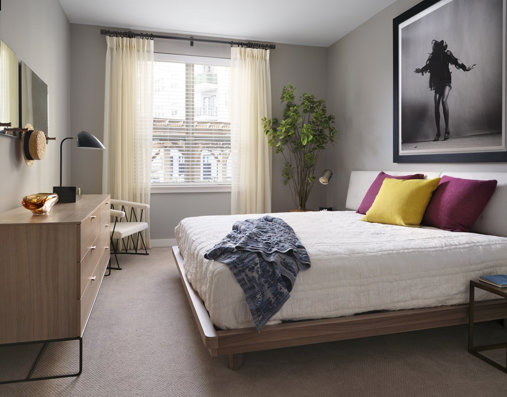 A bedroom with a large bed and a painting on the wall.