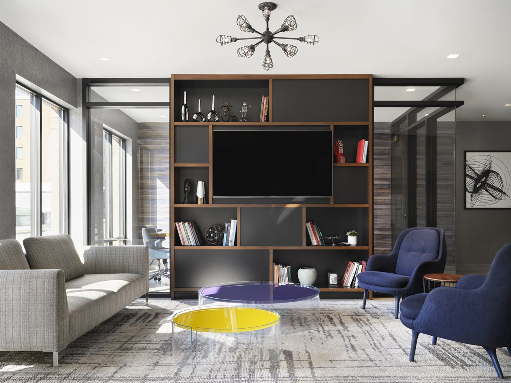 A living room with a grey sofa, a yellow coffee table, a black television and a blue chair.