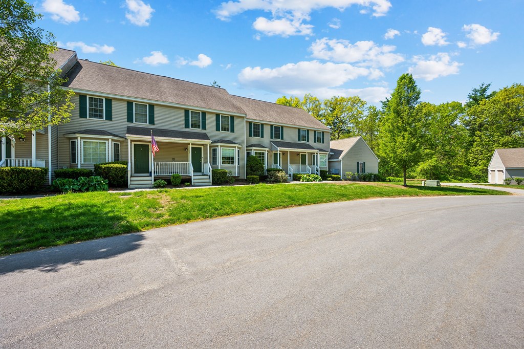 A row of houses with green lawns and trees in the background.