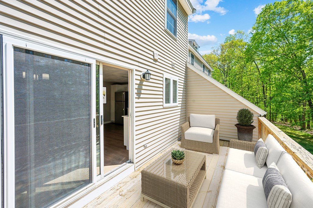 A patio area with a couch, chair, and table outside a house.