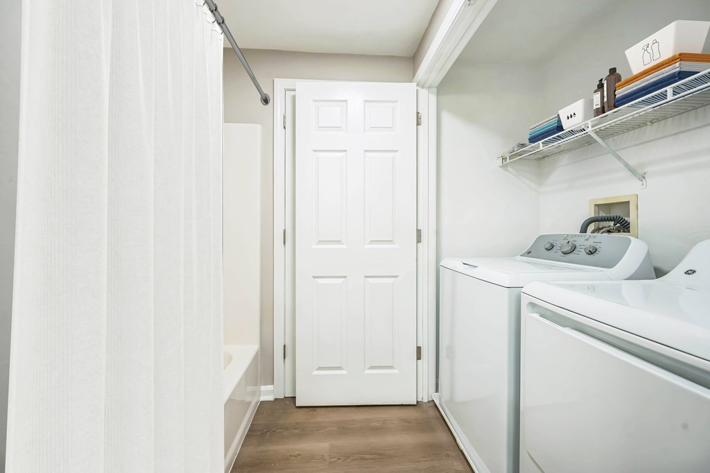 A white door is in a small room with a washer and dryer.