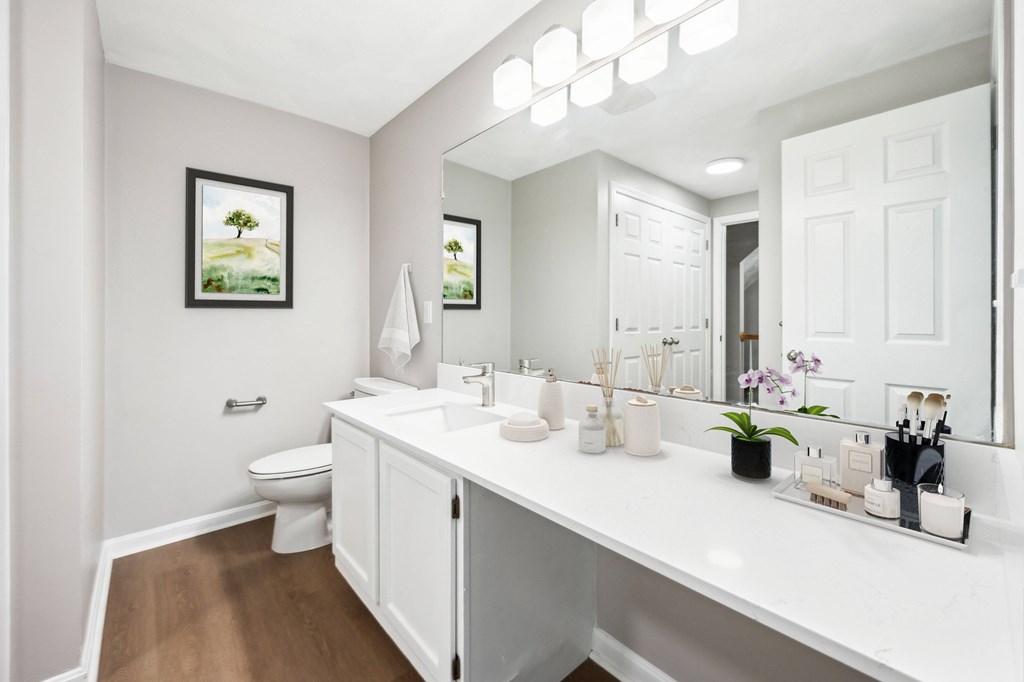 A white bathroom with a toilet, sink, and mirror.