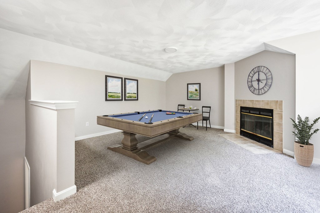 A pool table in a room with a fireplace and a clock on the wall.
