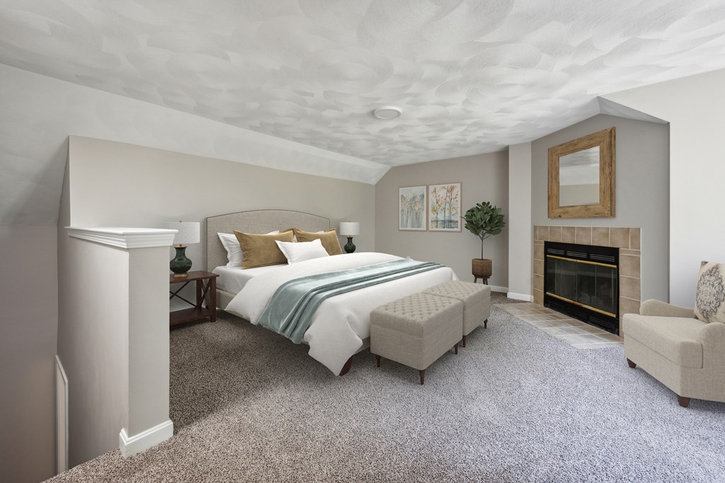 A bedroom with a large bed, a fireplace, and a chair.