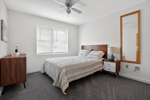 A bedroom with a bed, nightstand, and a ceiling fan.