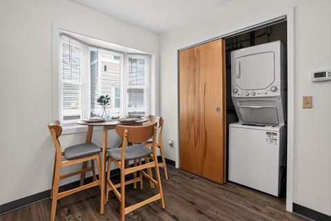 A small dining area with a table and chairs in front of a window.