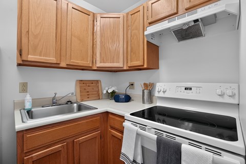 A kitchen with wooden cabinets and a white stove top oven.