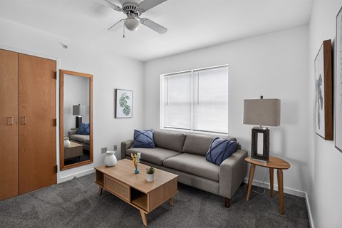 A living room with a grey couch, a wooden coffee table, and a ceiling fan.