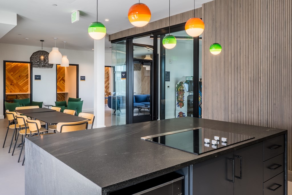 A modern kitchen with a black countertop and green chairs.