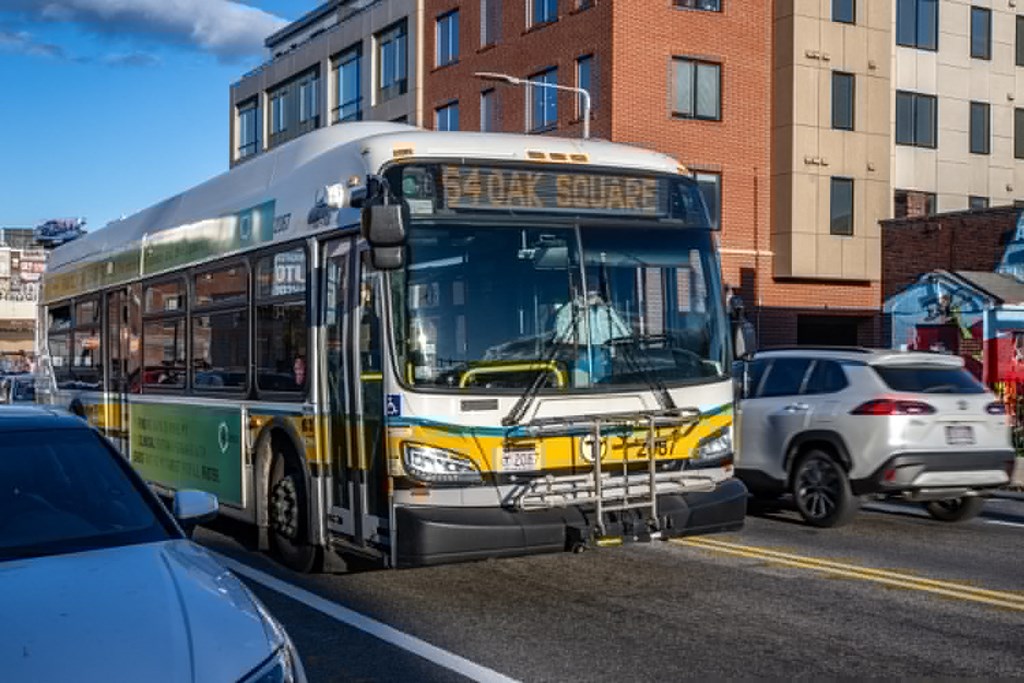a city bus driving down a busy city street at The Indie, Massachusetts, 02134