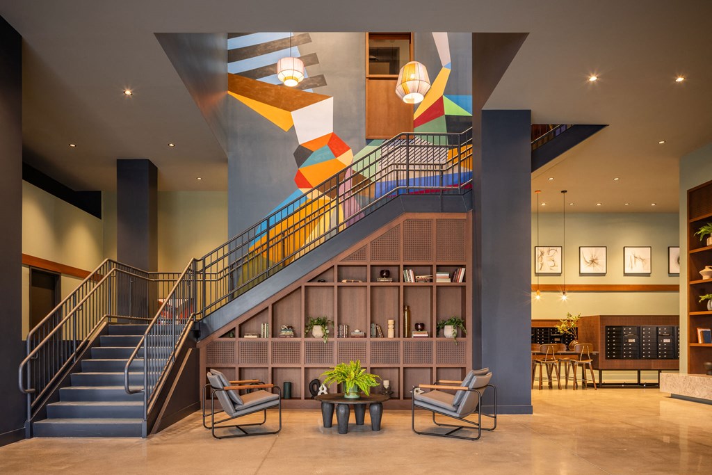 the lobby of a hotel with a staircase and chairs