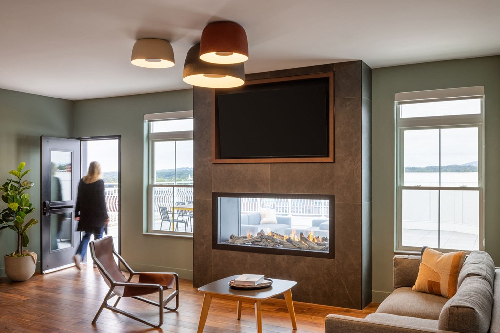 a living room with a fireplace and a woman walking through a door