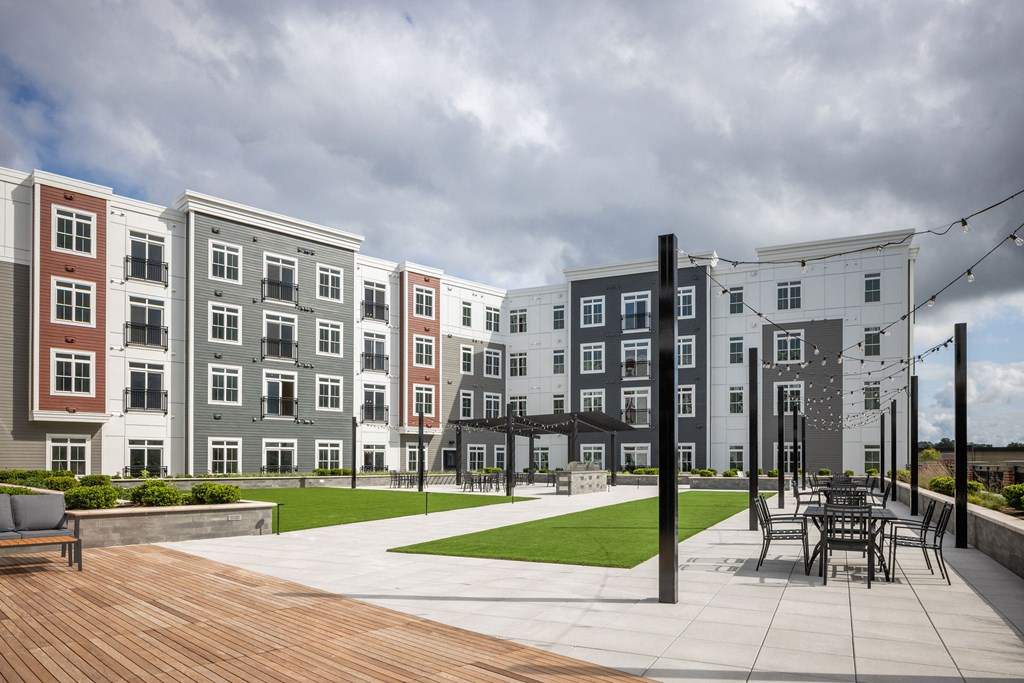 an exterior view of an apartment building with a patio and lawn