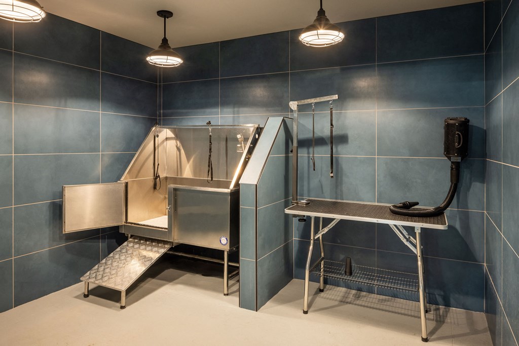 A clean, empty industrial kitchen with stainless steel appliances and a white floor.