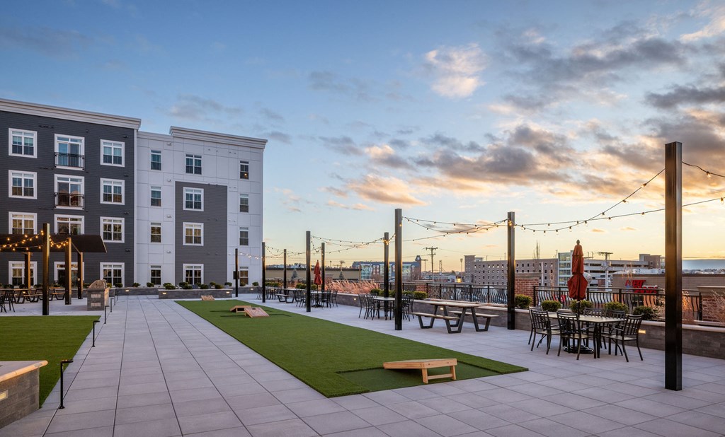 A rooftop patio with tables and chairs overlooks a city skyline.