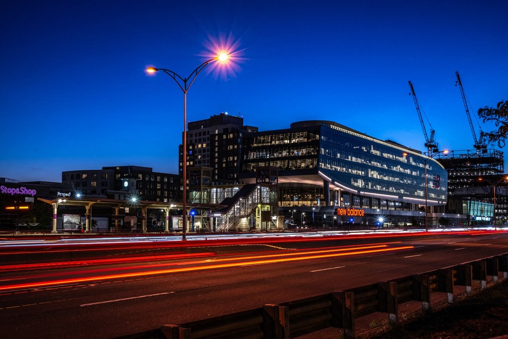 A view of Boston Landing lit up at night with cranes in the background and the Mass Pike in the foreground at The Indie, Boston  