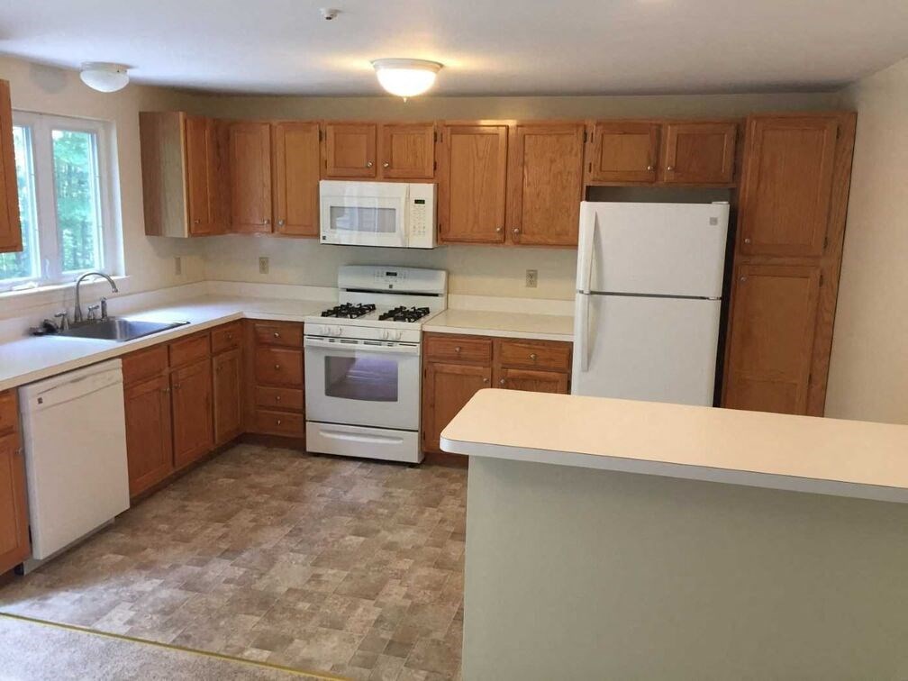 A kitchen with white appliances and wooden cabinets.