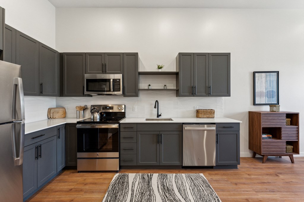 a kitchen with gray cabinets and stainless steel appliances