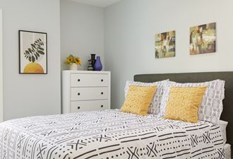 Model apartment bedroom with a bed and pictures on the wall at Atlantic Pointe in Brunkswick, ME