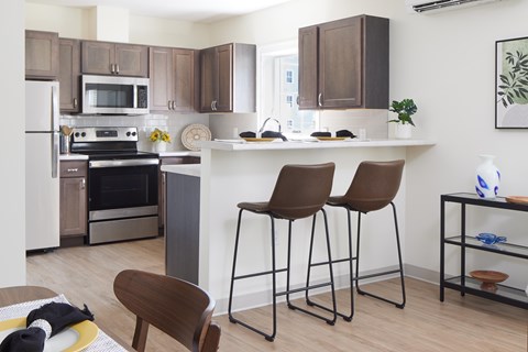 A kitchen with brown chairs and a white counter.