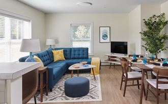 Model Apartment living room and dining room with a blue couch and a table and chairs at Atlantic Pointe in Brunkswick, ME