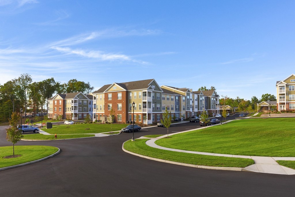A road with a car on it and apartment buildings on both sides.