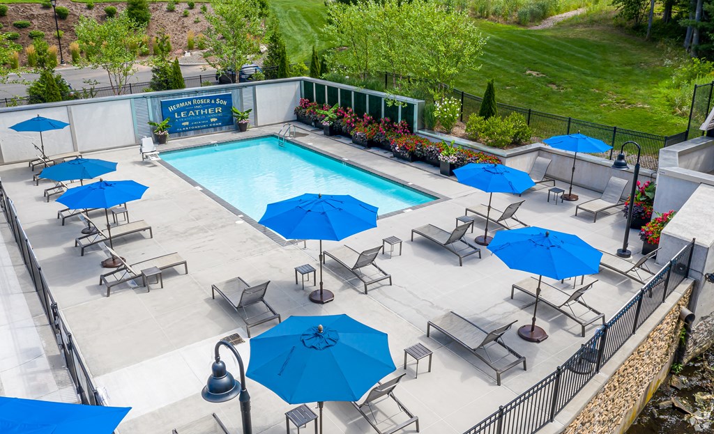 A pool surrounded by blue umbrellas and chairs.
