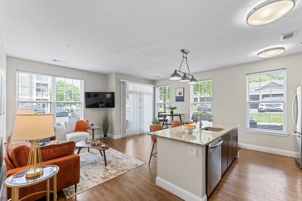 A well-lit kitchen and living room with a large island in the middle.