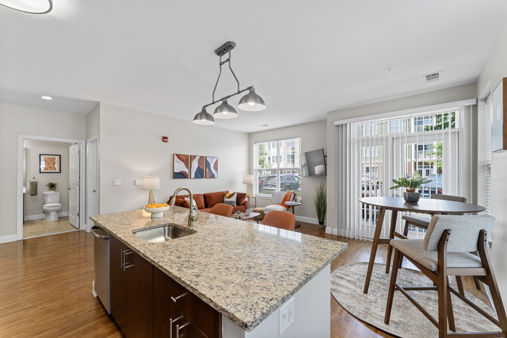 A kitchen with a granite countertop and wooden floors.