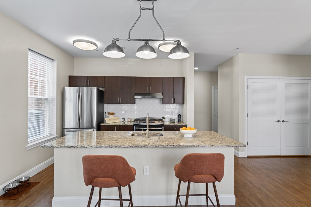 A kitchen with a granite countertop and two chairs.