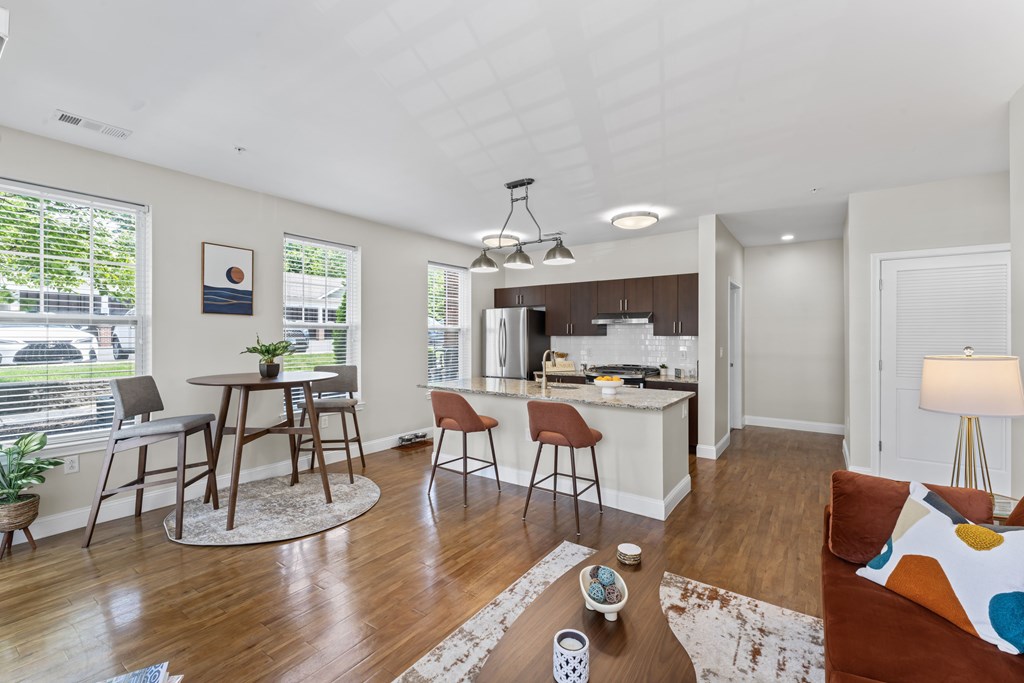 A well-lit, modern kitchen and living room with wooden floors and furniture.