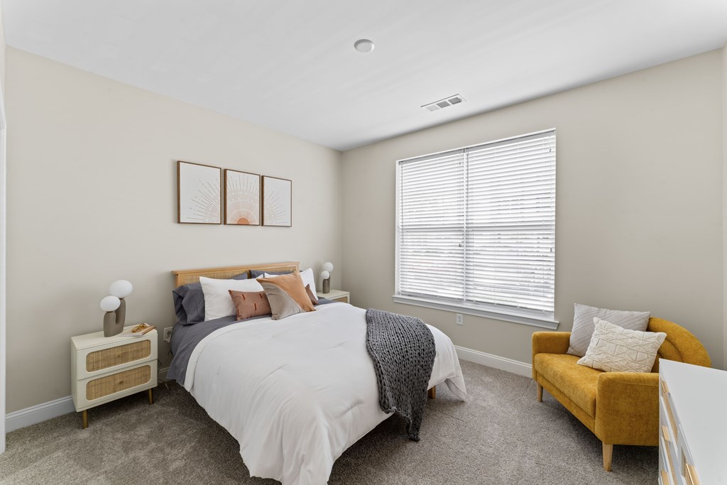 A bedroom with a bed, nightstand, and chair.