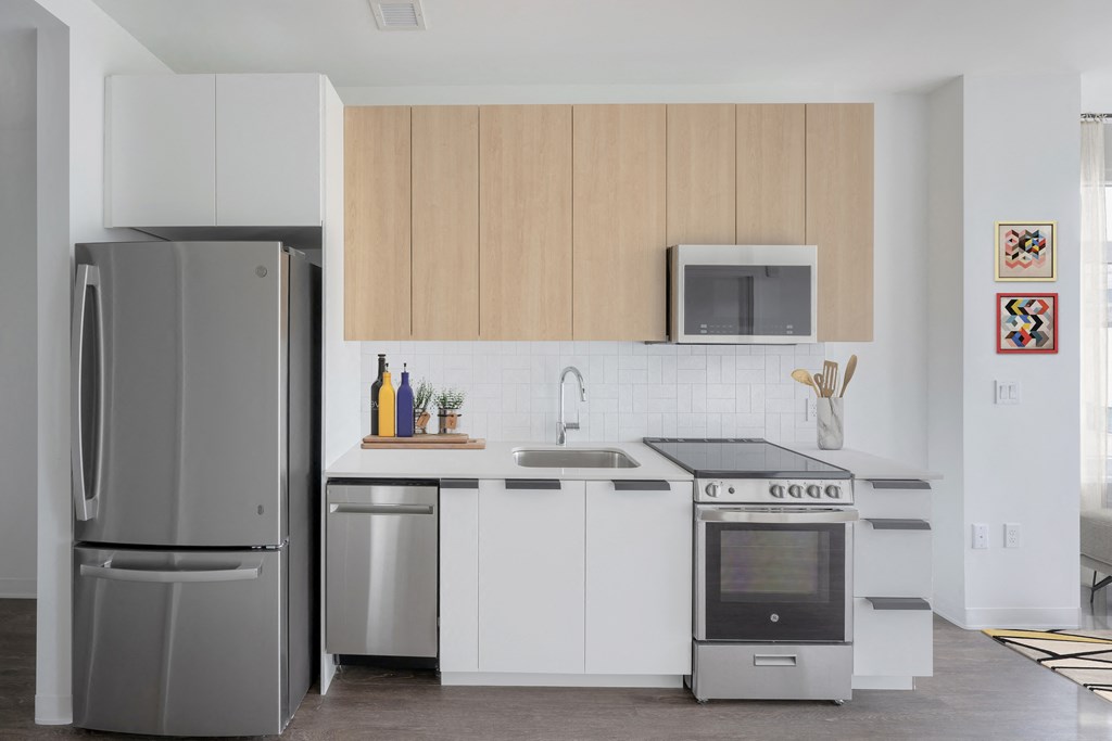 a kitchen with white cabinets and stainless steel appliances at The Indie, Boston, MA 02134  
