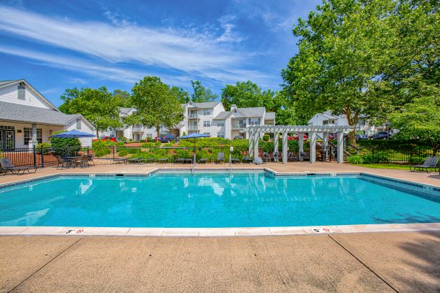 a swimming pool with trees and buildings in the background