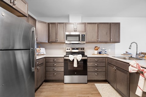 A kitchen with a refrigerator on the left and a stove top oven in the middle.