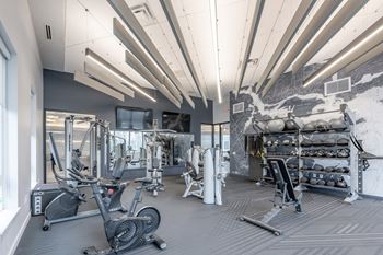 A gym with a variety of equipment including treadmills, weights, and exercise machines.