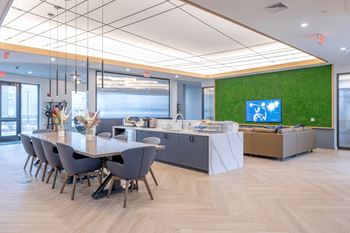 A conference room with a long table and chairs, a reception desk, and a green wall with a TV.