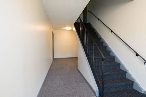 A staircase with a black railing and a grey carpet. at South Winds Apartments, Fall River, 02720