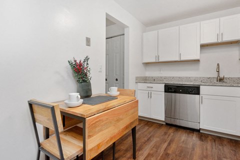 a kitchen with white cabinets and a wooden table with two chairs