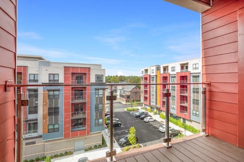 A view from a balcony of a parking lot and apartment buildings.