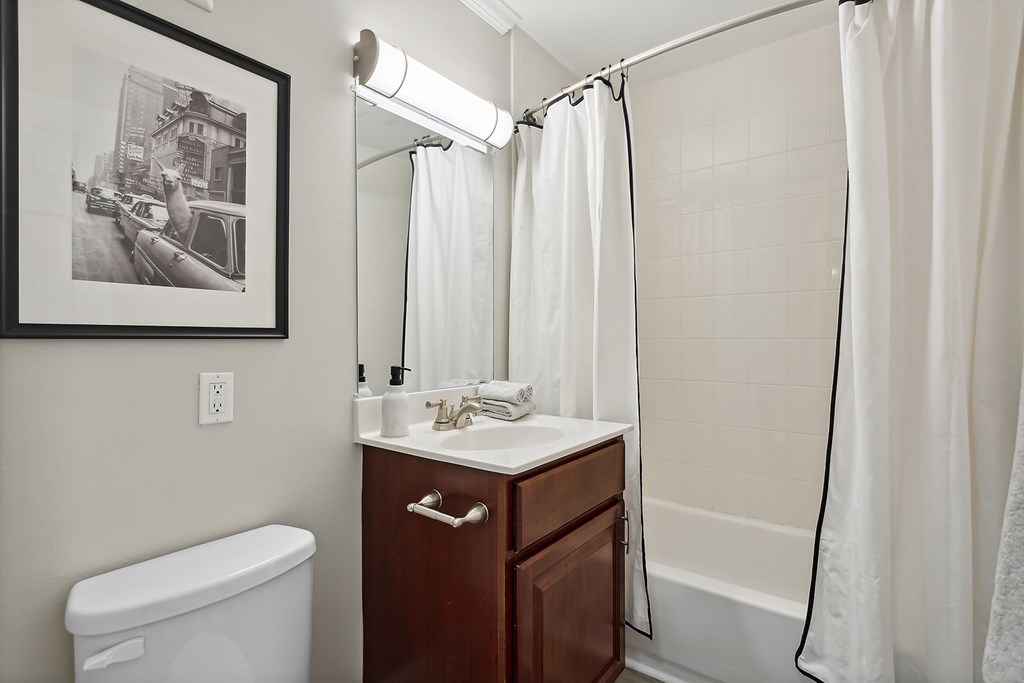 A bathroom with a white tub, sink, and shower curtain.