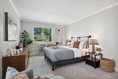 A bedroom with a large bed and a window overlooking a backyard.