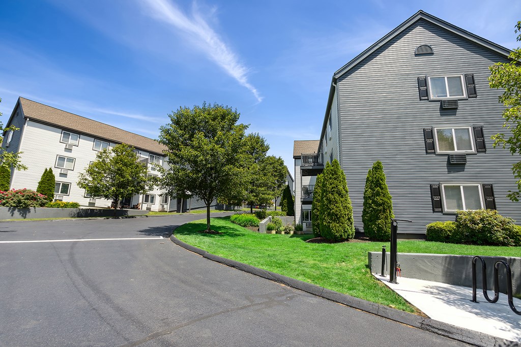 A sunny day at a residential area with two buildings and a tree.