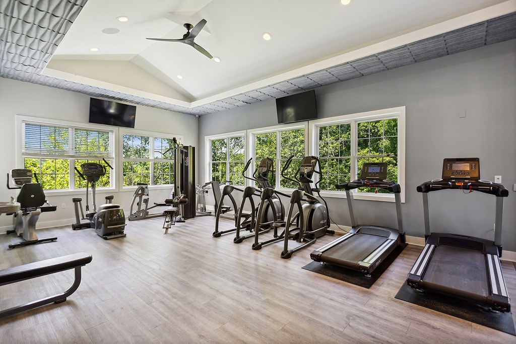 A spacious home gym with a variety of exercise equipment and a ceiling fan.