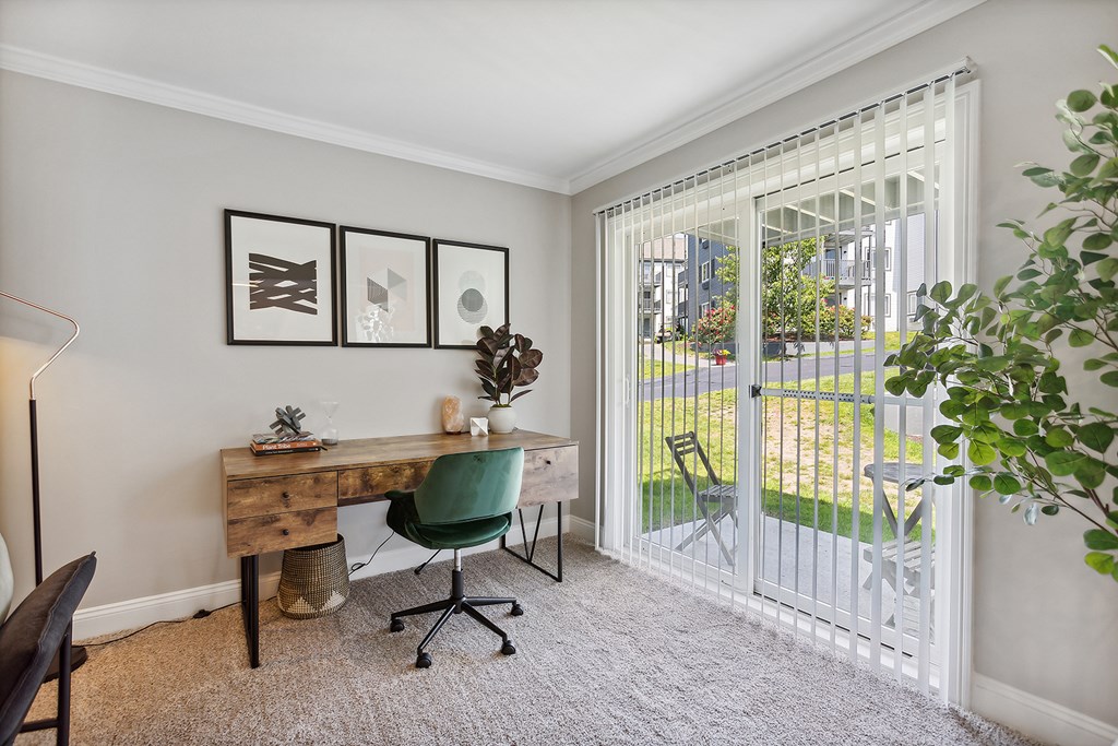 A room with a desk and a chair with a white fence outside.